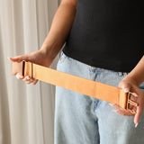 A woman holds an extended Size Extender strap in two hands. The Strap is Chekoh's signature strap colour in a golden brown, matching the buckles.