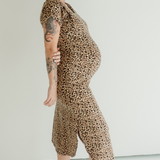 A pregnant woman wears the Chekoh Leopard print Journey Dress, standing barefoot and comfortable in a studio environment.