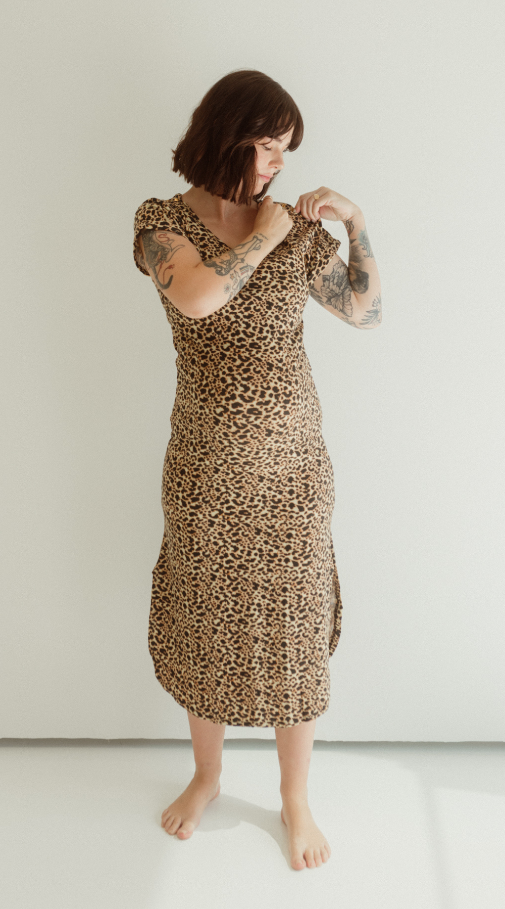 A pregnant mother demonstrates the pull down front feature of the Leopard print Journey Dress by Chekoh.