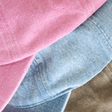Stack of three baseball caps in Pink, Lightwash Denim, and Bone on a white background.