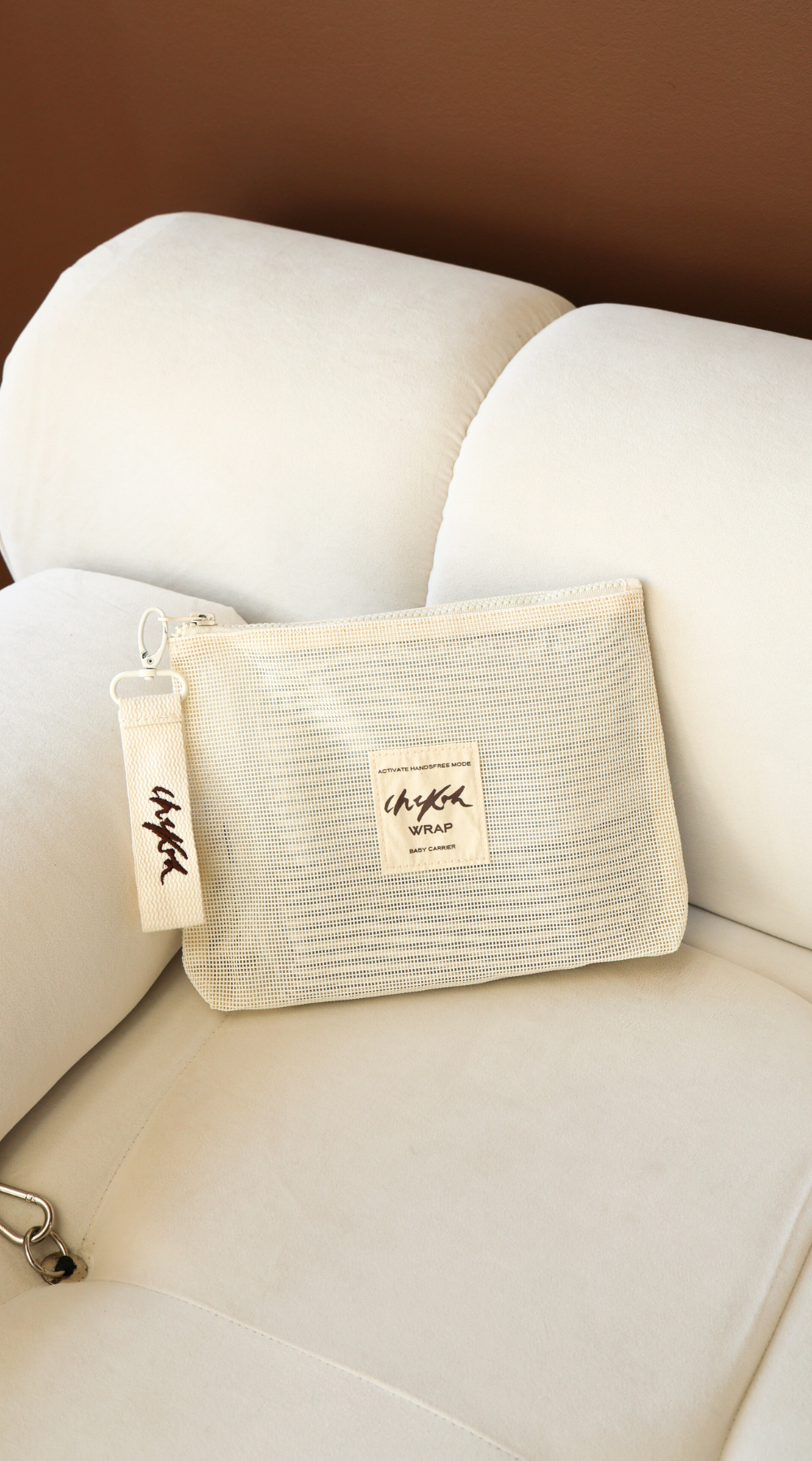 Beige Wrap Storage Bag Pouch by Chekoh Baby - sat on an off white couch in front of a brown wall.
