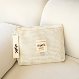Beige Sling Storage Bag Pouch by Chekoh Baby on an off white couch with brown background.