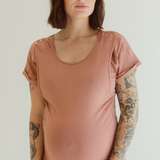 A pregnant mother wears the Dusk Journey Dress by Chekoh Baby. She is holding her pregnant belly and the dress is a soft dusky pink tone.