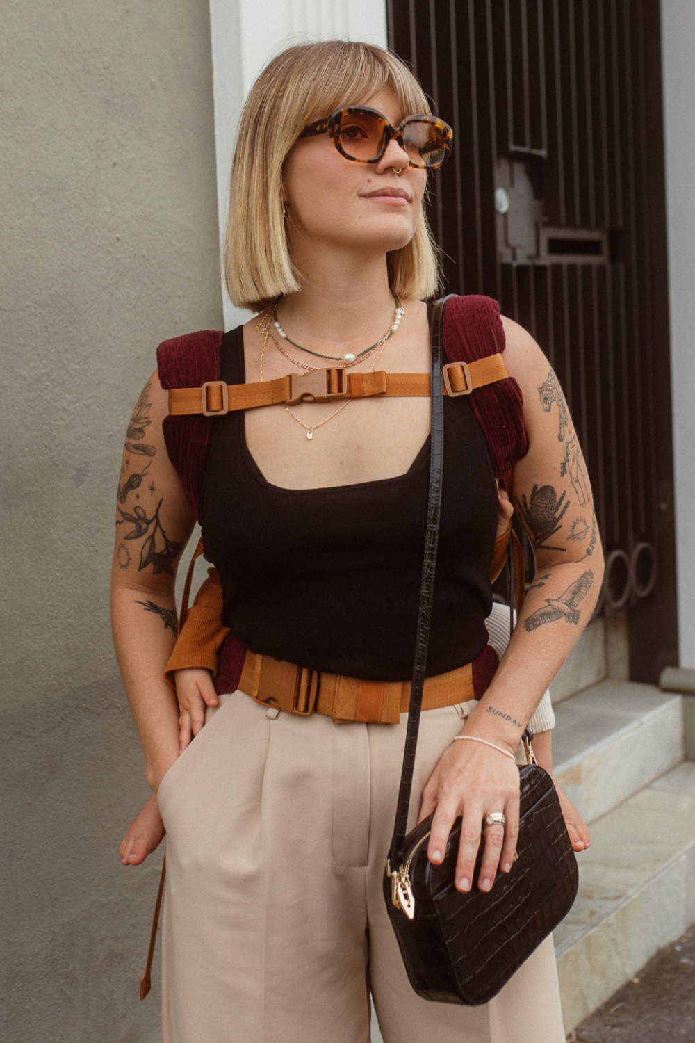 Example of how to use the Chekoh Chest Strap - woman is wearing her child in the Chekoh Clip Carrier in a back carry, using the Chest Strap across her chest for added support.