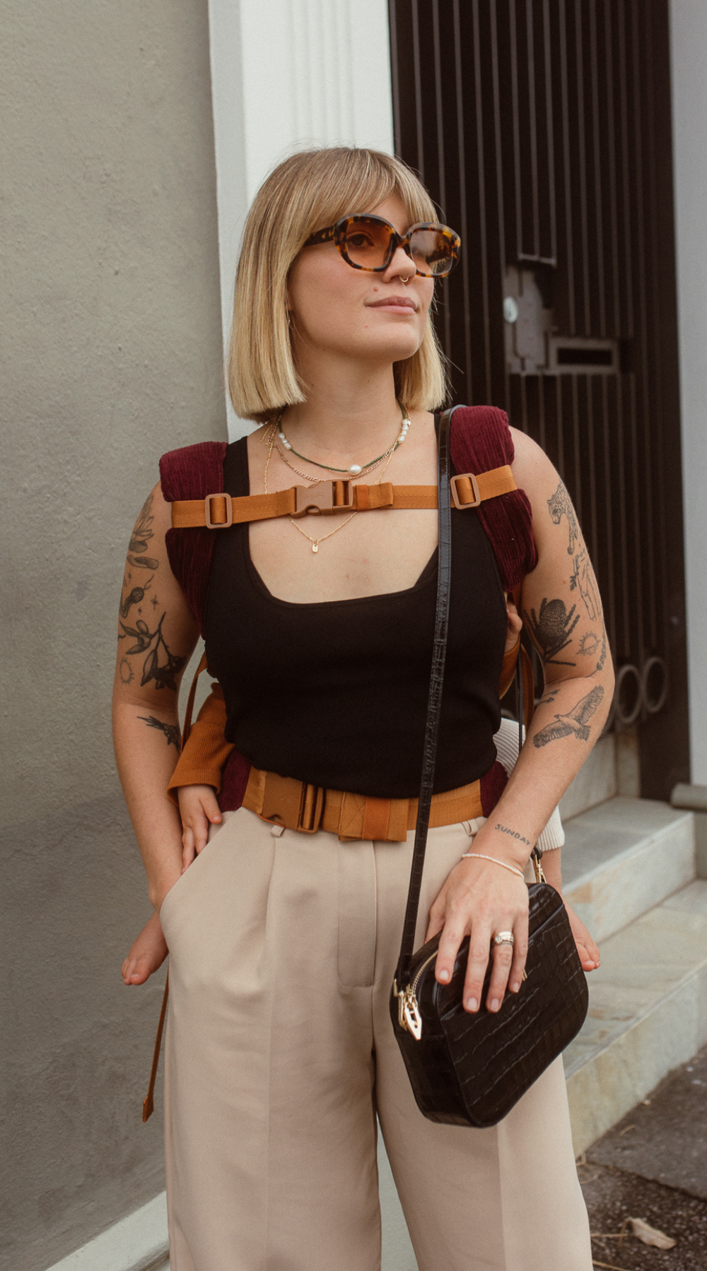 Example of how to use the Chekoh Chest Strap - woman is wearing her child in the Chekoh Clip Carrier in a back carry, using the Chest Strap across her chest for added support.