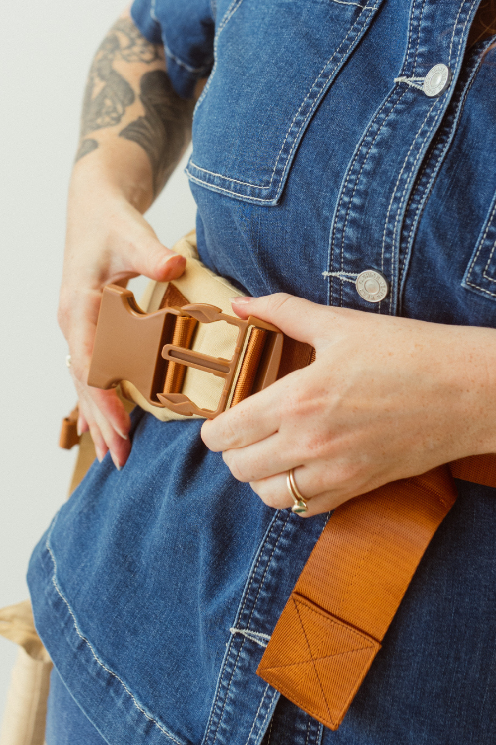 A woman is shown clipping in two sections of the Chekoh Clip Carrier Waistband Strap buckle. 