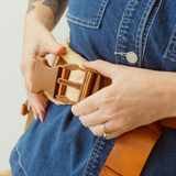 A woman is shown clipping in two sections of the Chekoh Clip Carrier Waistband Strap buckle. 