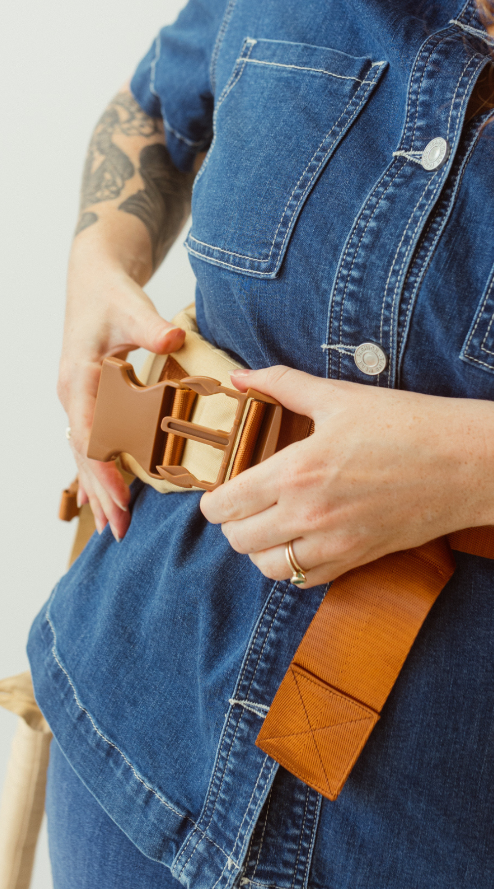 A woman is shown clipping in two sections of the Chekoh Clip Carrier Waistband Strap buckle. 