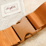 Close up image of the Chekoh Size Extender strap and buckle with a blurred vision of the matching cotton pouch.