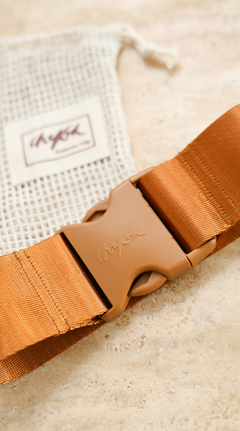 Close up image of the Chekoh Size Extender strap and buckle with a blurred vision of the matching cotton pouch.