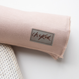 Close up details of the Chekoh Baby Cinta Swaddle Wrap - including the logo and soft fabric details. The colour is a soft nude, blush beige tone.