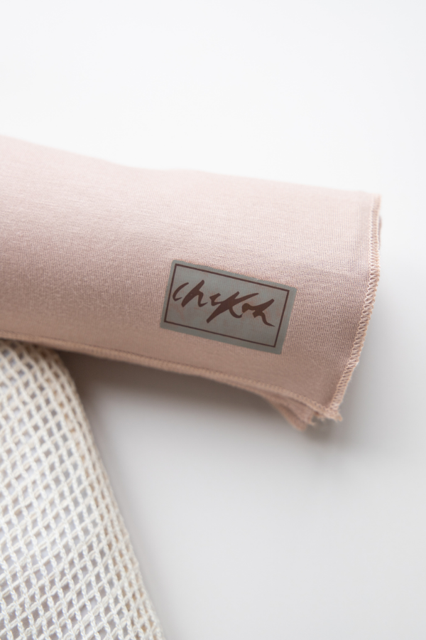 Close up details of the Chekoh Baby Cinta Swaddle Wrap - including the logo and soft fabric details. The colour is a soft nude, blush beige tone.
