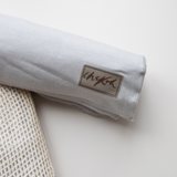 Close up detail of the Chekoh logo on the soft grey toned Asha Swaddle Baby Wrap by Chekoh Baby.