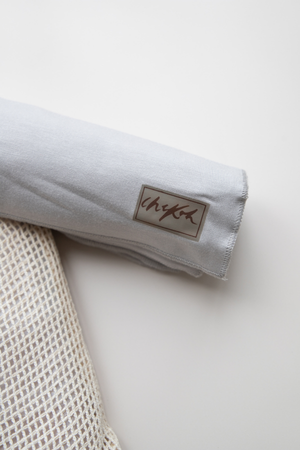 Close up detail of the Chekoh logo on the soft grey toned Asha Swaddle Baby Wrap by Chekoh Baby.