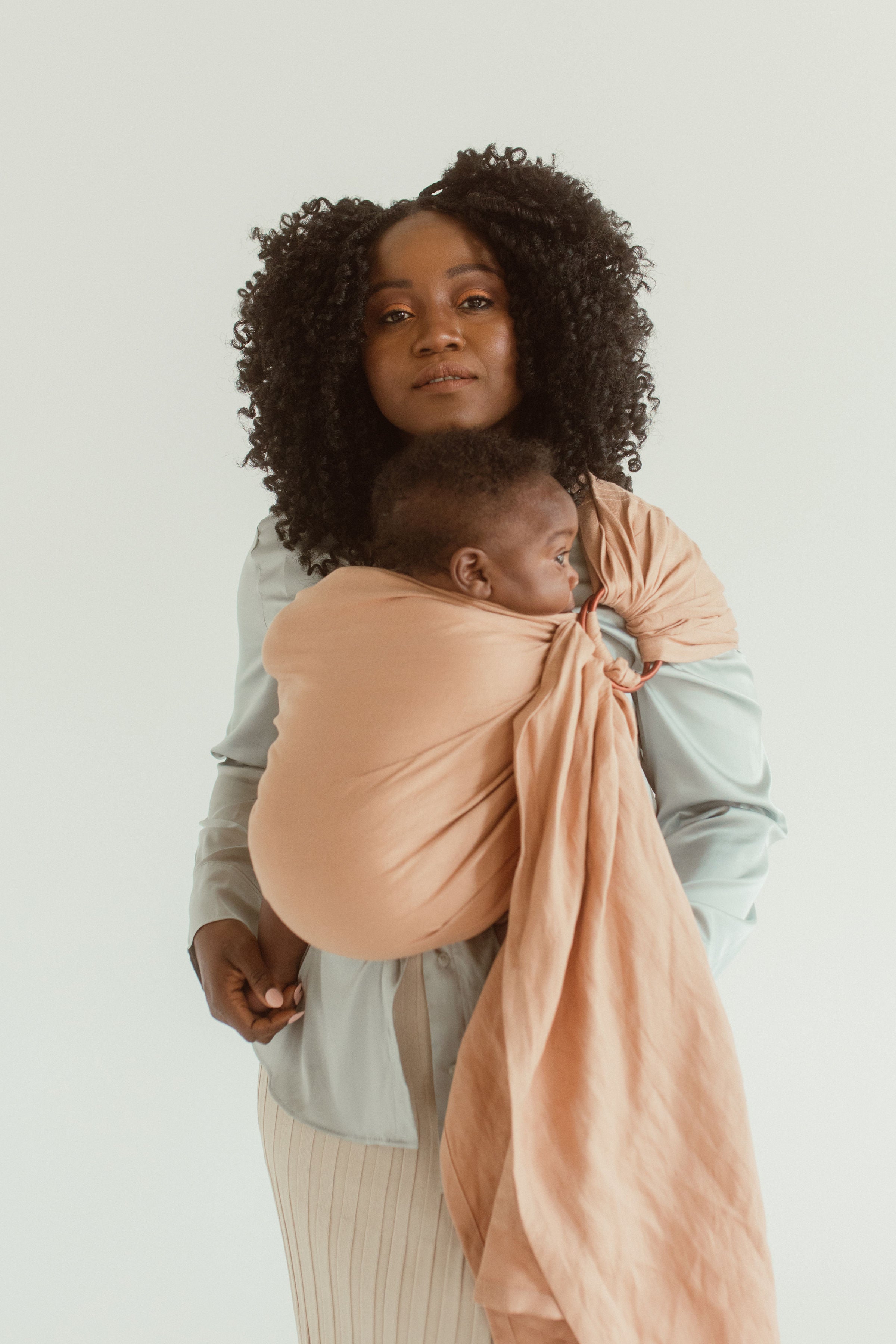 A mom wears the Chekoh Ring Sling in the shade Terracotta 