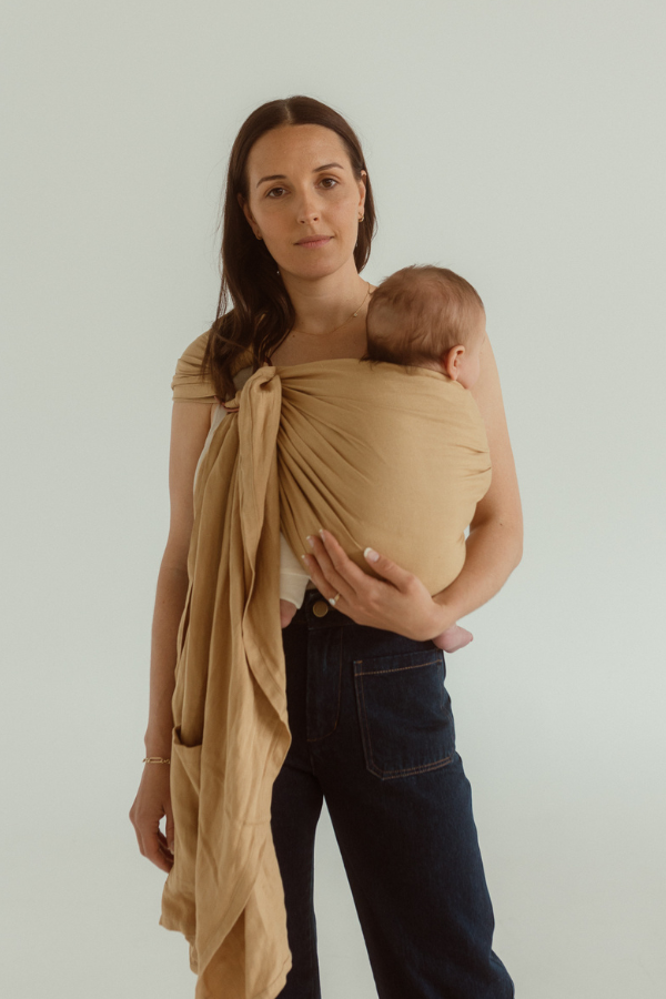 A mother holds her baby close wearing an Australian designed Baby Carrier by Chekoh. It is a Ring Sling Carrier, worn across one shoulder. 