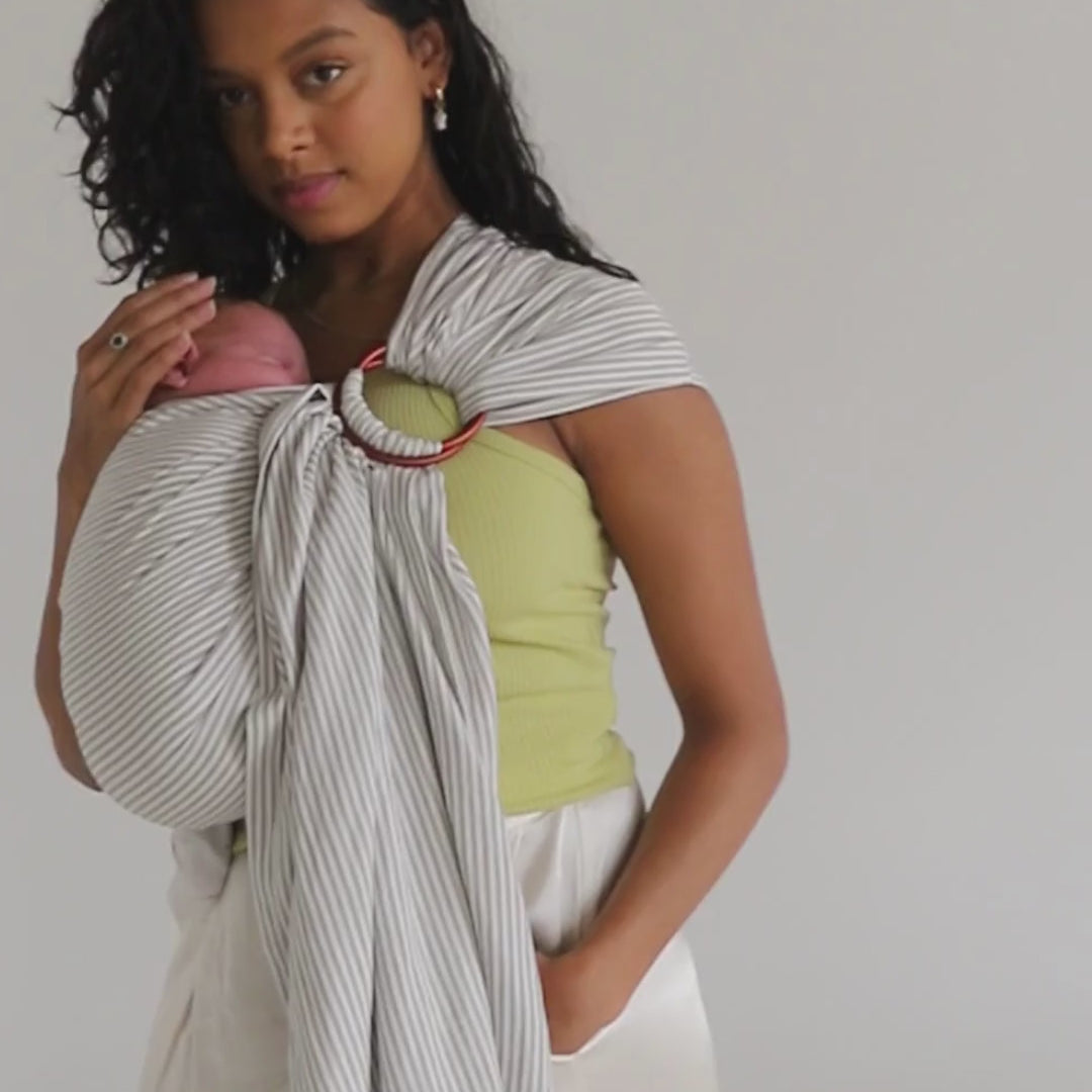 A mother shows off how comfortable the Chekoh Baby Ring Sling is, wearing her little one in the Grey Stripe print. 