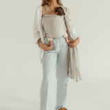 A mother wears her newborn baby close in a Ring Sling Carrier, in the shade Asha - a neutral soft grey tone.